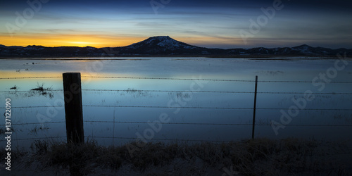 Flooded field at sunset with fence post and barbed wire.  Sierra Valley Wetlands, Northern California. © neillockhart