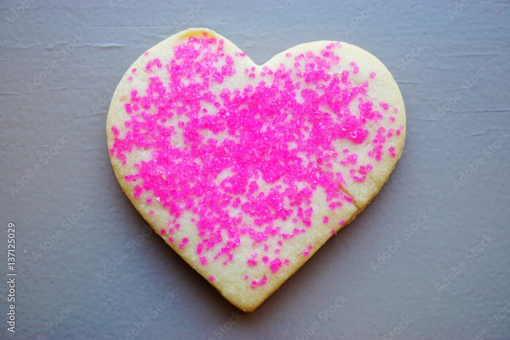 Obraz premium A heart shaped sugar cookie with red and pink sprinkles for Valentine's Day