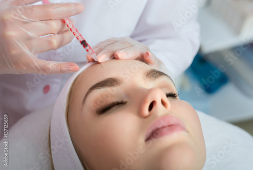 Young woman gets beauty facial injections in salon.