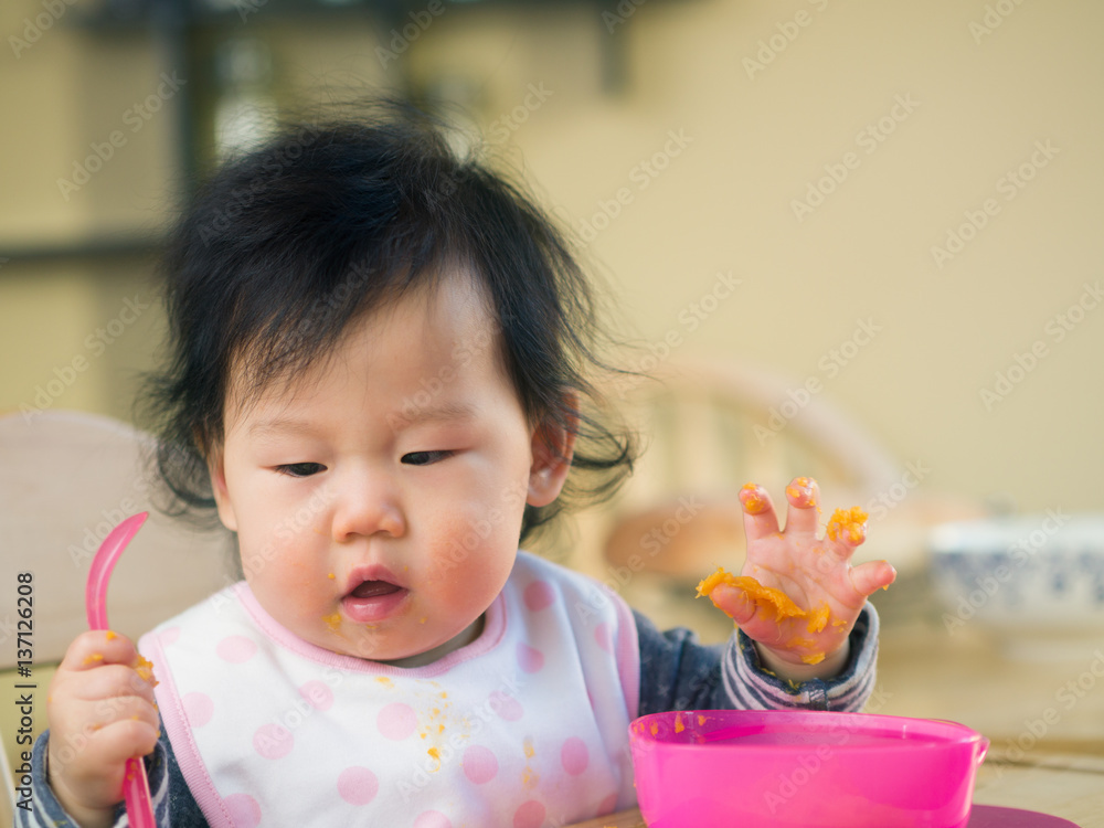 baby girl eating mashed sweet potatoes