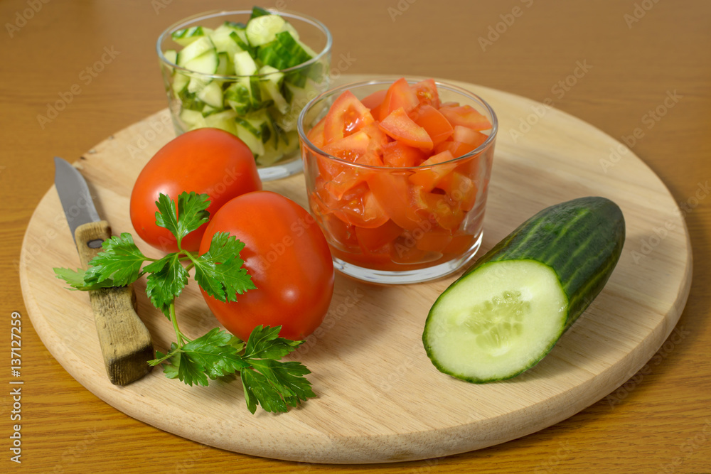 Whole cucumbers, tomatoes and salad of them on a cutting board. Whole cucumbers, tomatoes and salad of them on a cutting board.