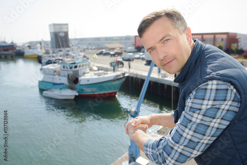 Man leaning on railing on harbour