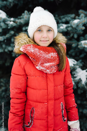 portrait of a girl in a red jacket, near the green tree on the street