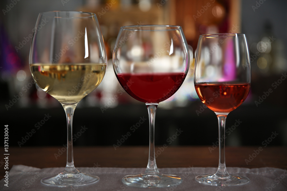 Three glasses with tasty wine in bar on bright background