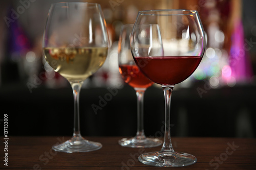 Three glasses with tasty wine in bar on bright background