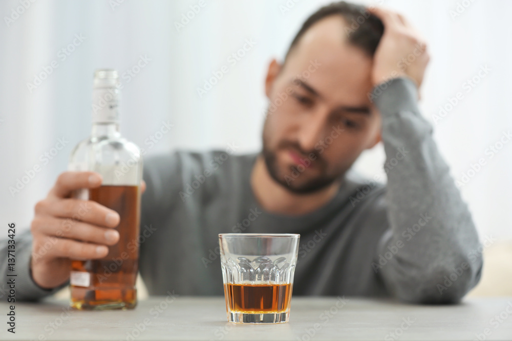 Glass with whisky on table and blurred man on background Glass with whisky on table and blurred man on background