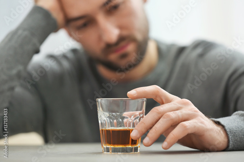 Lonely depressed man drinking whisky at home, closeup