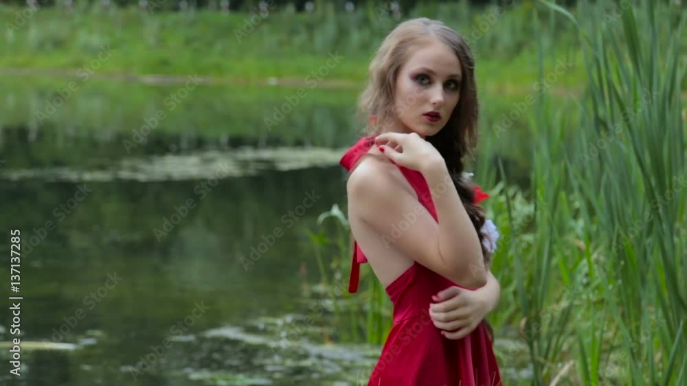 Portrait of unusual and mysterious girl with creative make-up and elegant hairstyle with flowers in ethnic red dress. Nature background. Fashion, mysterious and make up concept Portrait of unusual and mysterious girl with creative make-up and elegant hairstyle with flowers in ethnic red dress. Nature background. Fashion, mysterious and make up concept