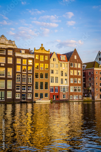 Traditional old buildings and boats at sunset in Amsterdam, Netherlands.