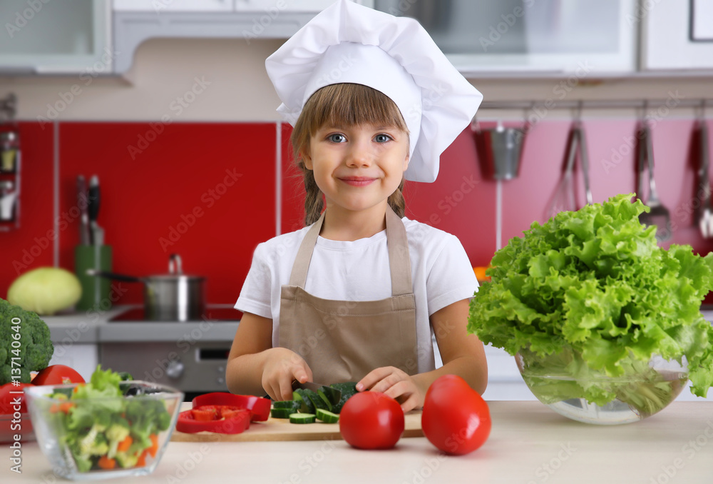 Small girl chef cutting vegetables in kitchen Small girl chef cutting vegetables in kitchen