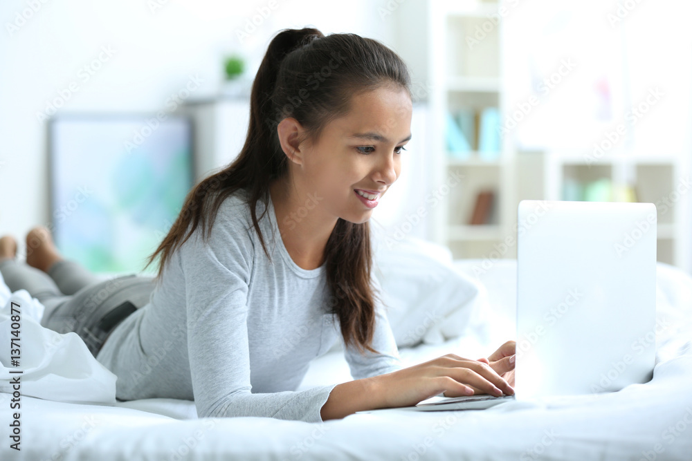 Cute girl lying on bed with laptop Cute girl lying on bed with laptop