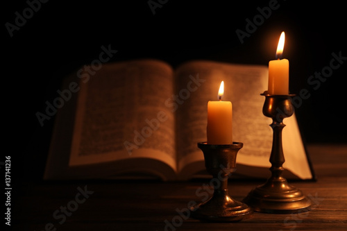 Burning candles and Bible on background