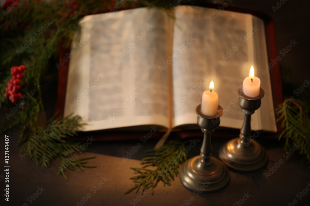 Burning candles and blurred open Bible on grey table Burning candles and blurred open Bible on grey table