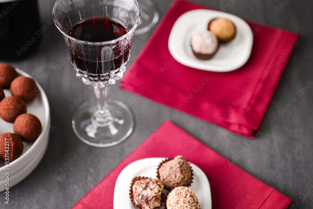 Delicious chocolate truffles and red wine on grey background Delicious chocolate truffles and red wine on grey background