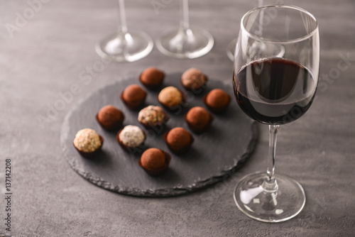 Cuadro en lienzo Delicious chocolate truffles and red wine on grey background