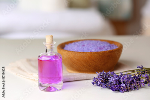 Bottle of essential oil with lavender and sea salt on background