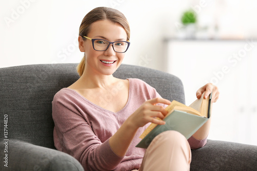 Young woman reading book on...