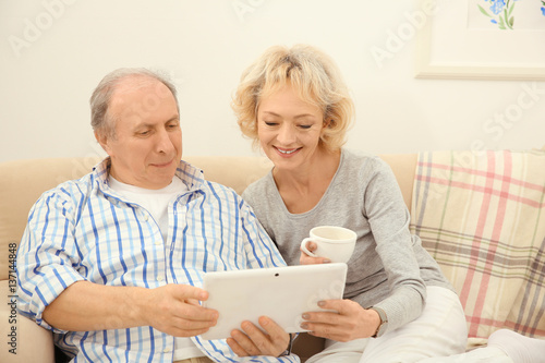 Senior couple making video call from tablet computer at home