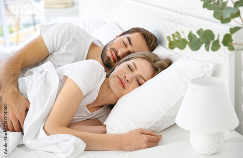 Young cute couple sleeping together in bed