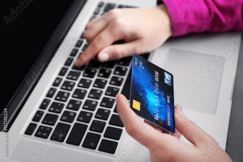 Woman holding credit card and using laptop, closeup