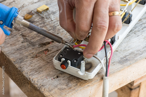 This man repairing a damaged power cord. Welding lead to the wires, using Electric Soldering Gun.