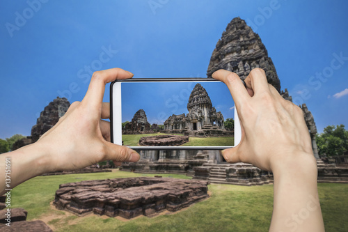 Tourist using smartphone to take a picture of  Prasat Hin Phimai in Nakonratchasima, Thailand photo