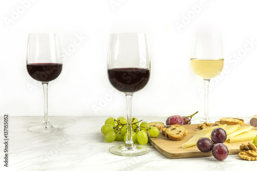 Red and white wine with cheese, bread and grapes