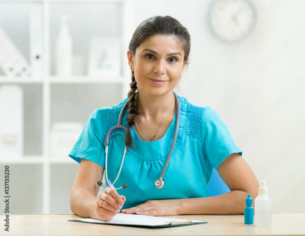Adorable woman doctor writes sitting at table in the office Adorable woman doctor writes sitting at table in the office