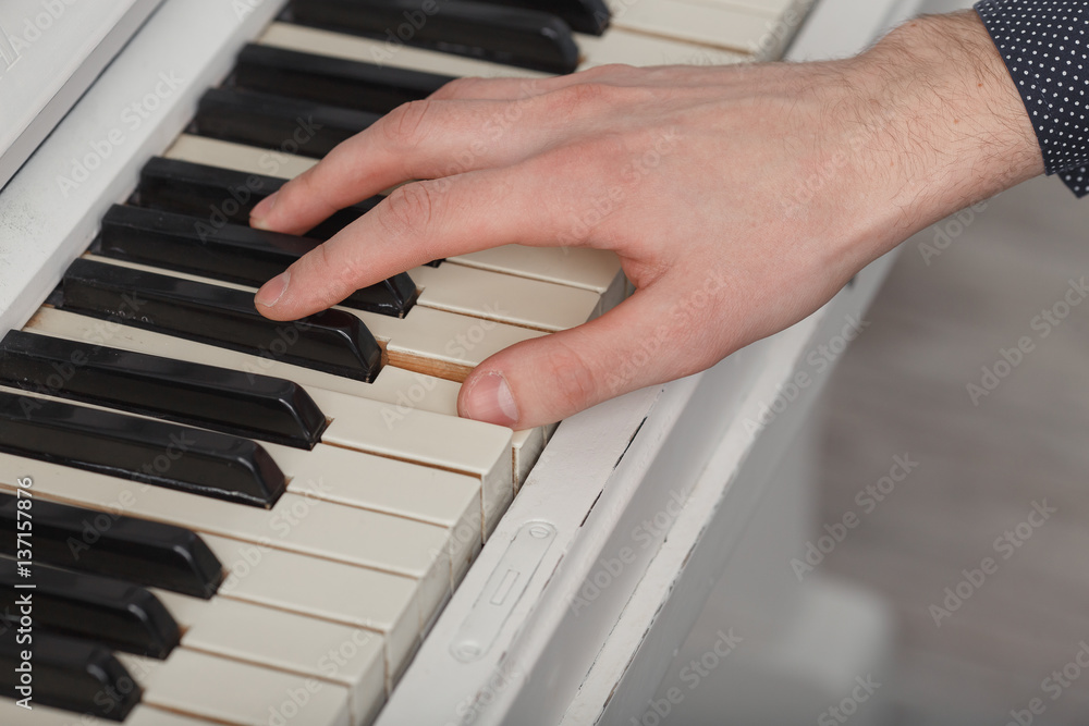 Obraz premium A young man playing piano closeup. Music and hobby concept