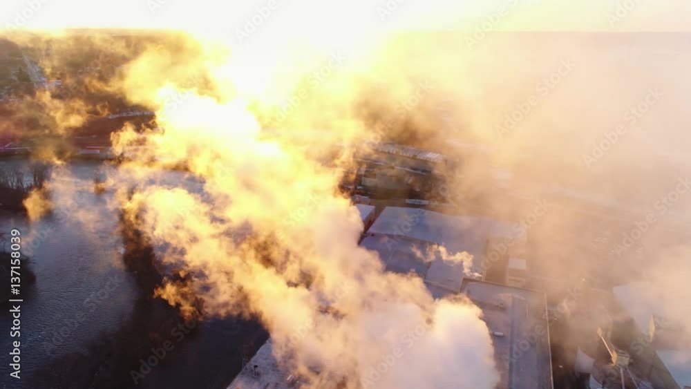 Aerial flyby of beautiful smokestack emissions illuminated in the sunrise.
Aerial flyby of beautiful smokestack emissions illuminated in the sunrise.
