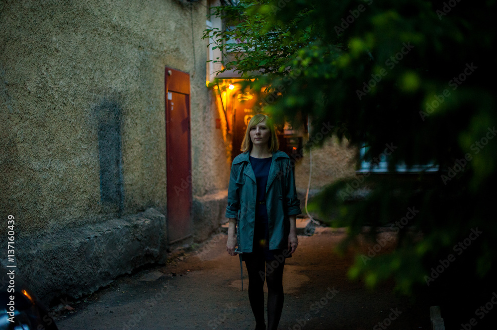Obraz premium outdoor portrait of young blonde woman, wearing a raincoat, smoking electronic cigarette