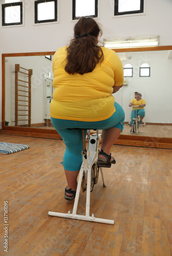 overweight woman exercising on bike simulator