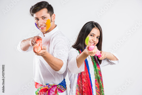 Indian Couple showing their colored hands or with pichkari or sweet laddu on Holi festival, isolated over white background