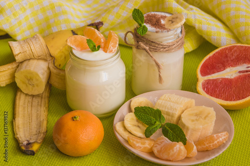 .Organic homemade sweet milk dessert with banana, cinnamon, tangerine, red orange and mint on the wooden table