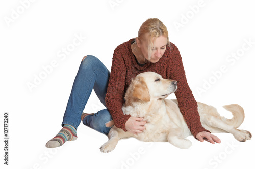 Studio shot of blond middle aged woman sitting with the Golden Retriever dog on the white background. The womnan is looking at the dog. photo