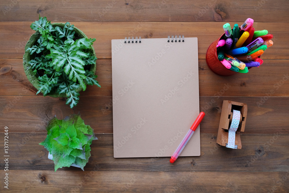 Blank notebook paper, pens and small plants on wood table background