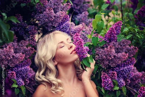 Beautiful Woman Enjoying the Smell of Lilac. Cute Model and Flowers. Aromatherapy and Spring Concept