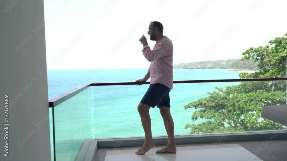 Young man relaxing, admire view and drinking water standing on terrace
Young man relaxing, admire view and drinking water standing on terrace