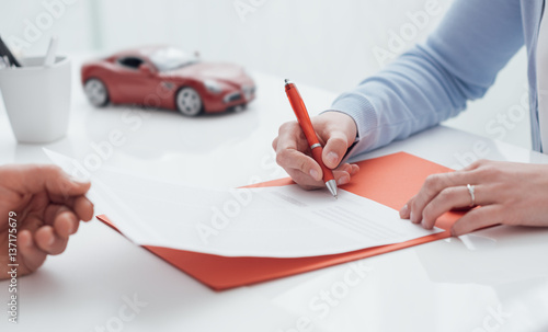 Driver signing a car insurance photo