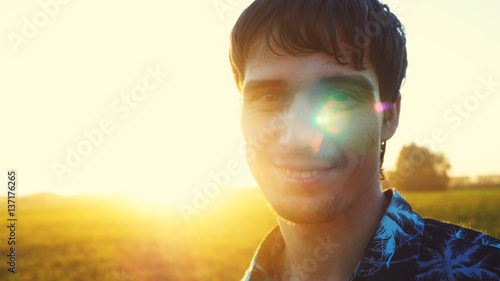 Valokuva Portrait of smiles young man looking at the sun during beautiful sunset with lense flare effects