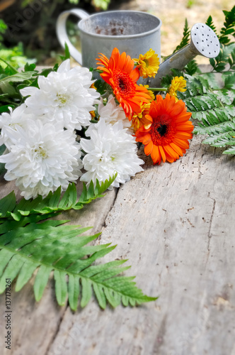 bouquet de fleur et arrosoir sur planche en bois