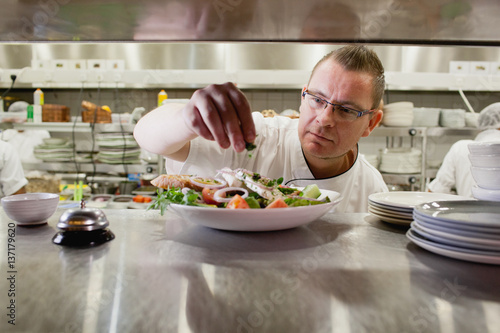 Chef preparing dish at restaurant.