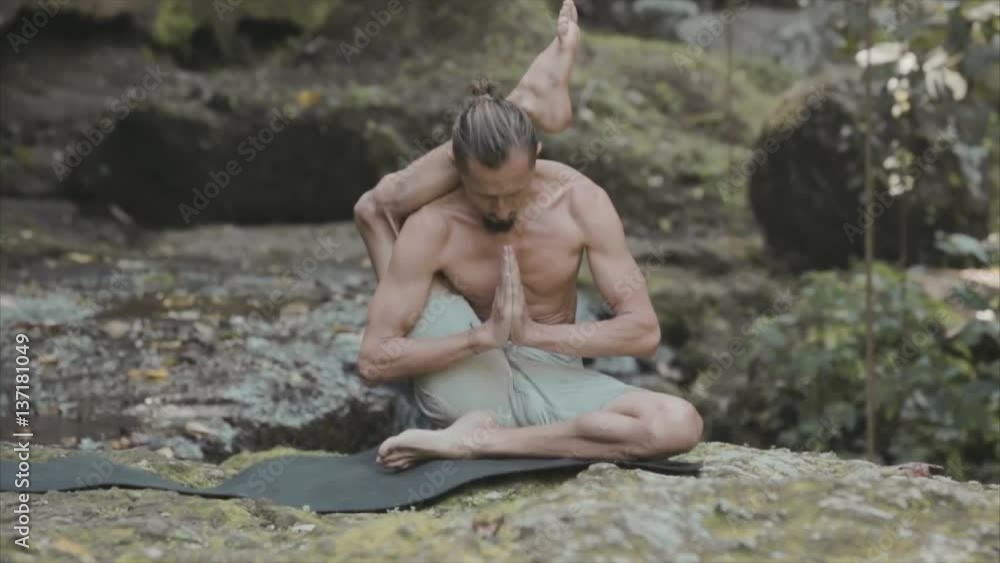 Young man practicing yoga fitness exercises outdoors on a jungle background. Meditation and relaxation Young man practicing yoga fitness exercises outdoors on a jungle background. Meditation and relaxation