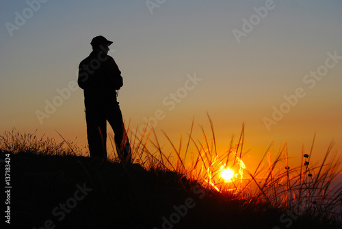 Silhouette of man watching sunrise high on mountain