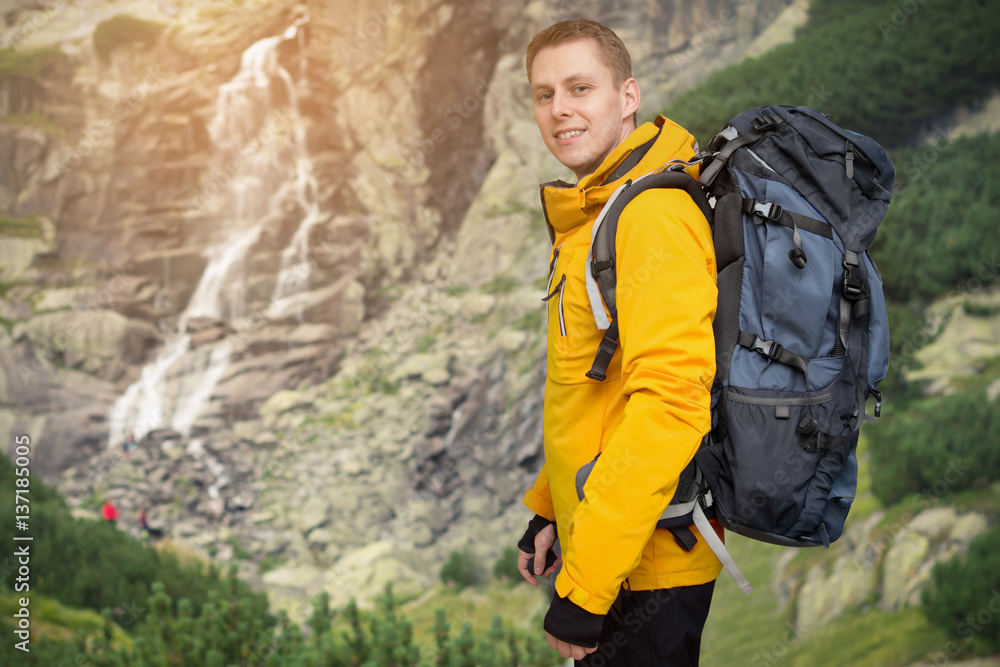 hiker man with backpack standing at waterfall