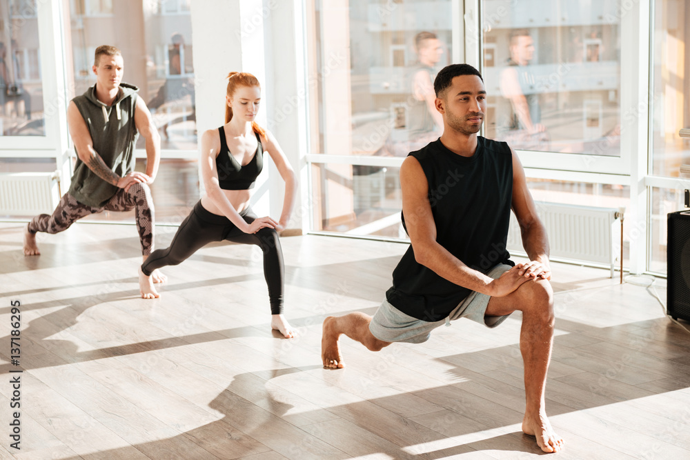 Obraz premium Group of barefoot people doing yoga exercises in studio