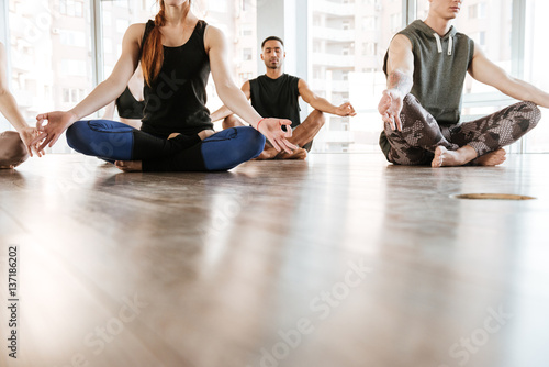 Group of people meditating in lotus pose with eyes closed