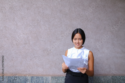 Pretty girl smiling, posing, holds paper in hands and looking aw photo