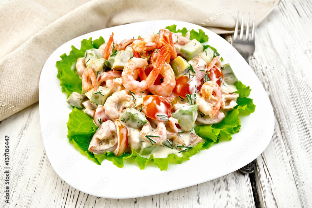 Salad with shrimp and avocado in white plate on light board Salad with shrimp and avocado in white plate on light board