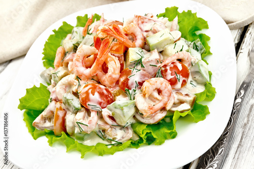 Salad with shrimp and avocado in plate on board